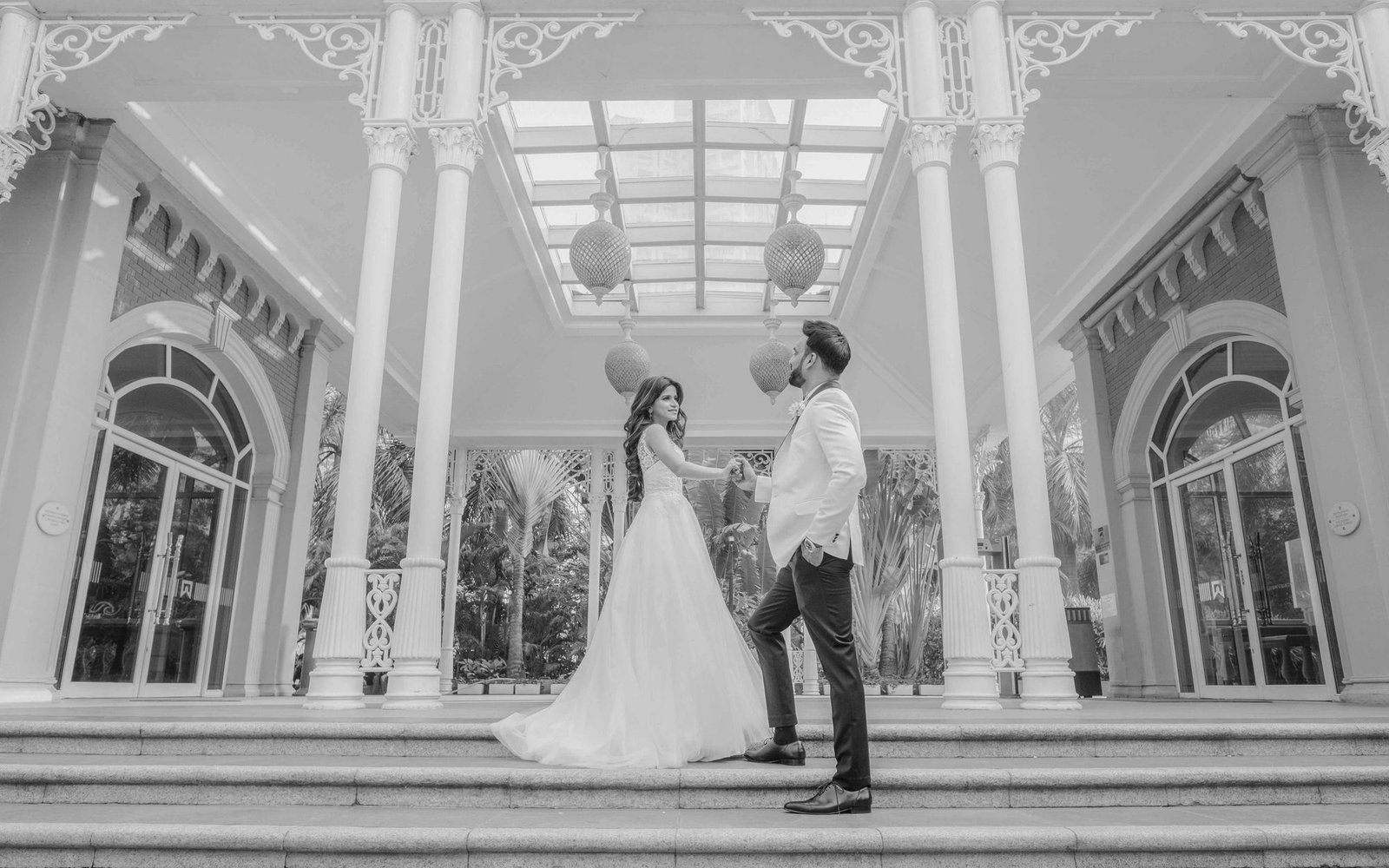 A couple framed by palace arches, in black and white